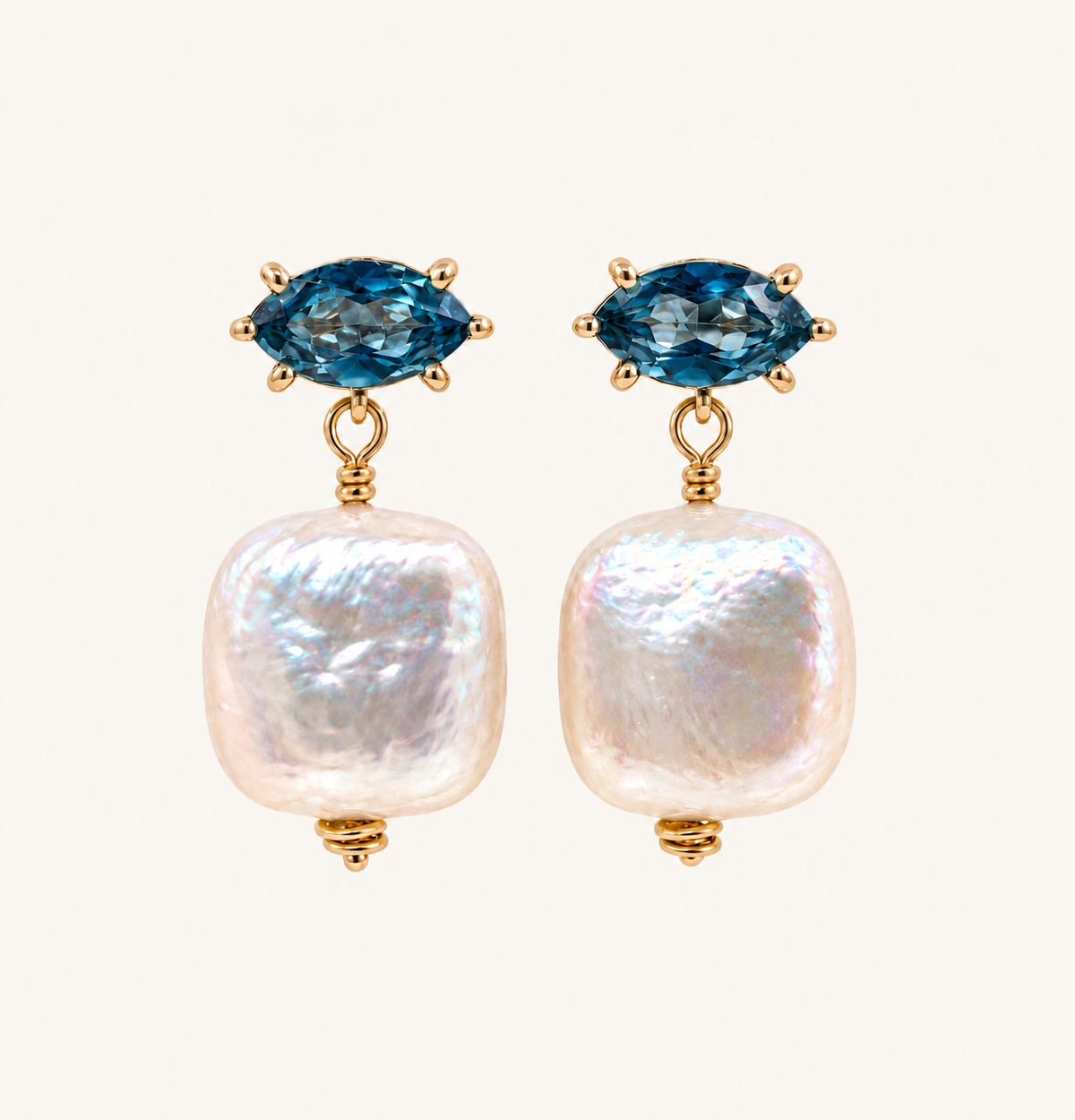 A pair of gold drop earrings featuring marquise-cut blue gemstones at the top and large, irregular white baroque pearls hanging below