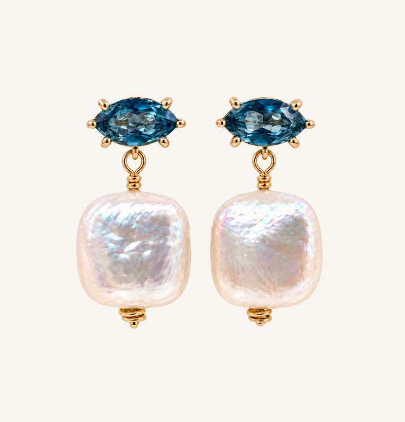 A pair of gold drop earrings featuring marquise-cut blue gemstones at the top and large, irregular white baroque pearls hanging below