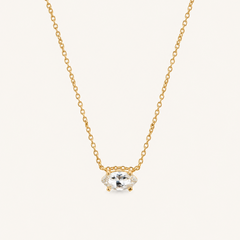 Close up of a natural white sapphire necklace on a delicate gold chain.