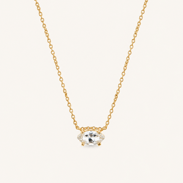 Close up of a natural white sapphire necklace on a delicate gold chain.