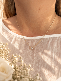 A delicate gold chain necklace with a natural white sapphire shown on a model wearing a wedding dress. 