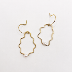 Gold sculptural earrings with pearl accents on a white background