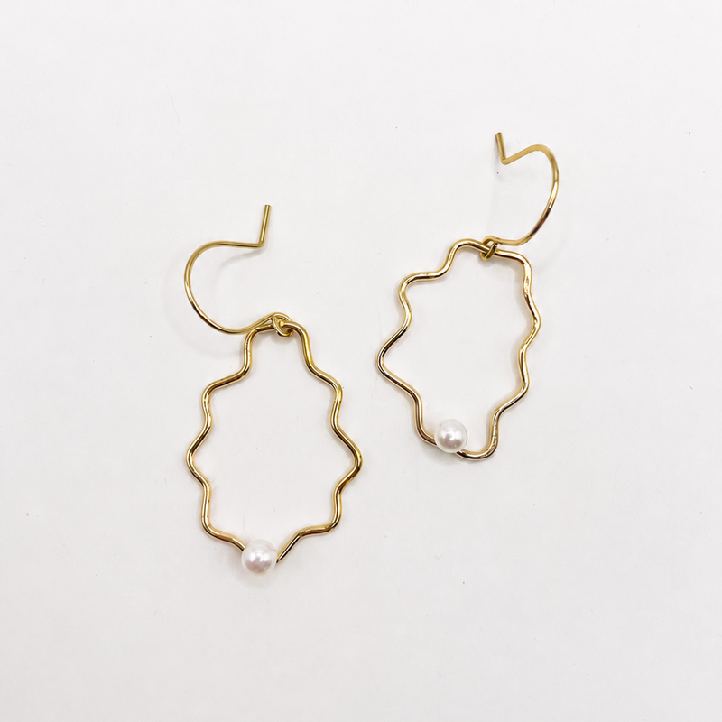 Gold sculptural earrings with pearl accents on a white background