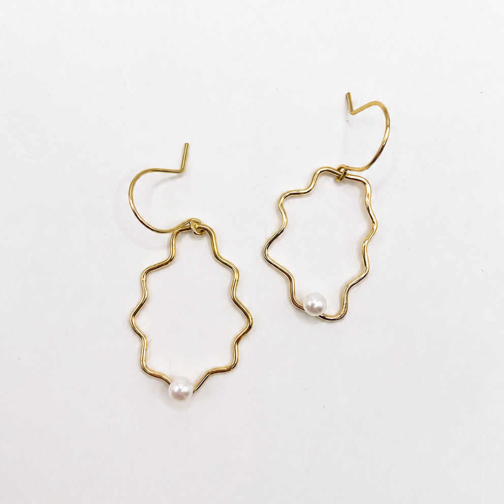 Gold sculptural earrings with pearl accents on a white background