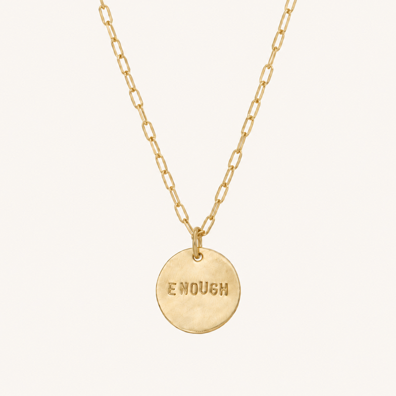 Gold necklace with the word enough on the pendant