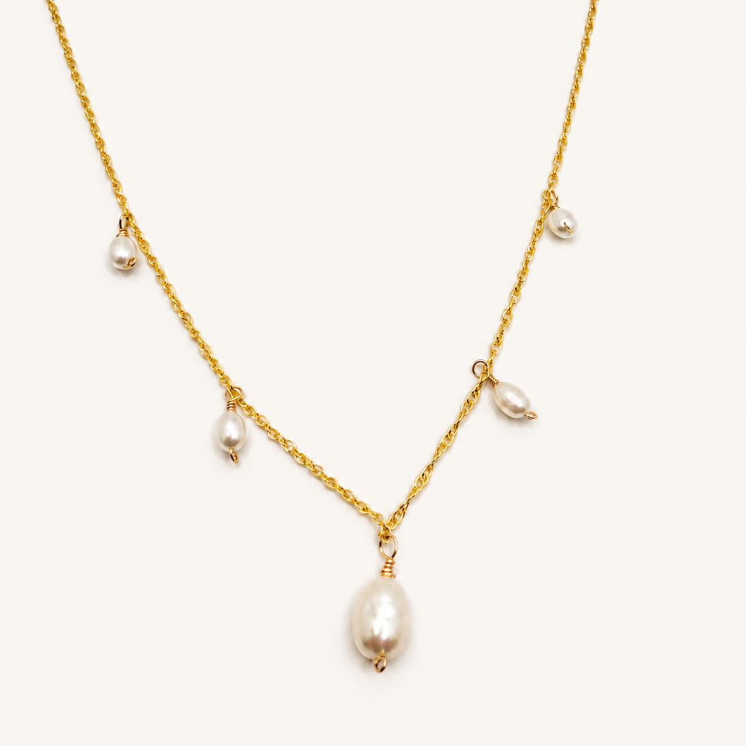 Close-up of cascading freshwater pearls on delicate gold chain.”
