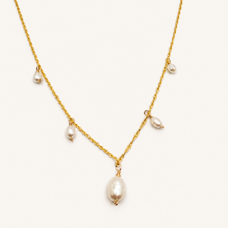 Close-up of cascading freshwater pearls on delicate gold chain.”