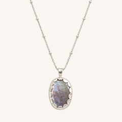 A silver beaded chain necklace with an oval pendant featuring iridescent mother-of-pearl inlay, shown against a solid off-white background.