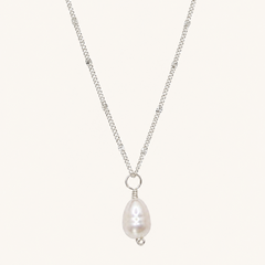 A silver chain necklace featuring a teardrop-shaped white pearl pendant with a small silver bead accent, displayed against a solid off-white background.