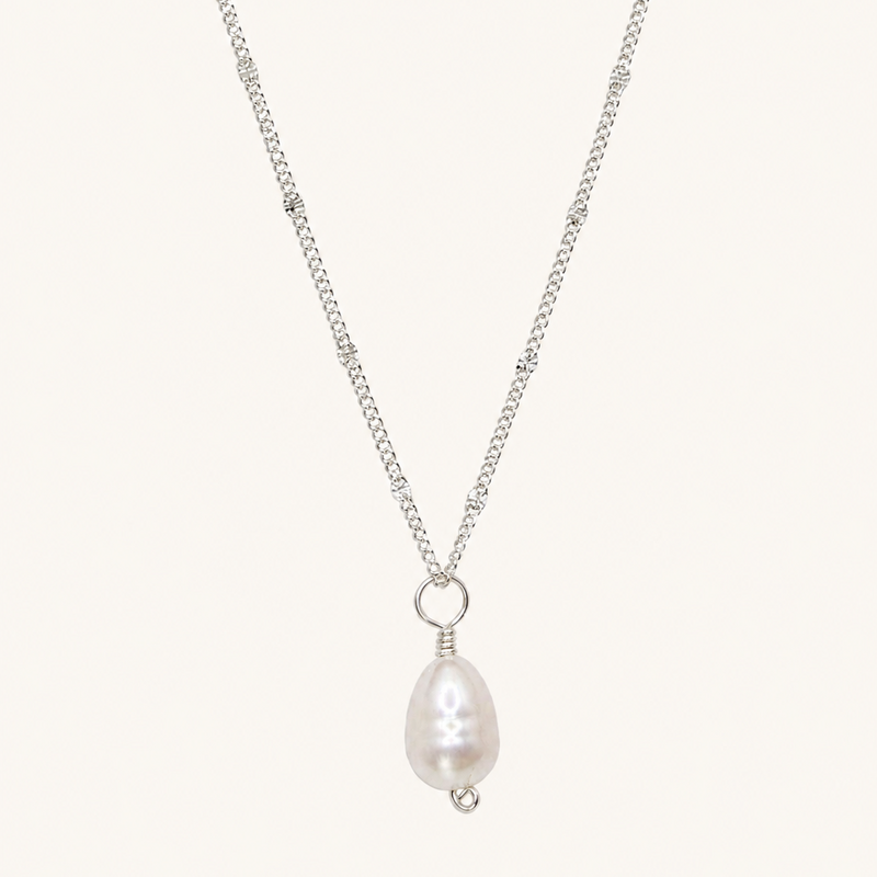 A silver chain necklace featuring a teardrop-shaped white pearl pendant with a small silver bead accent, displayed against a solid off-white background.